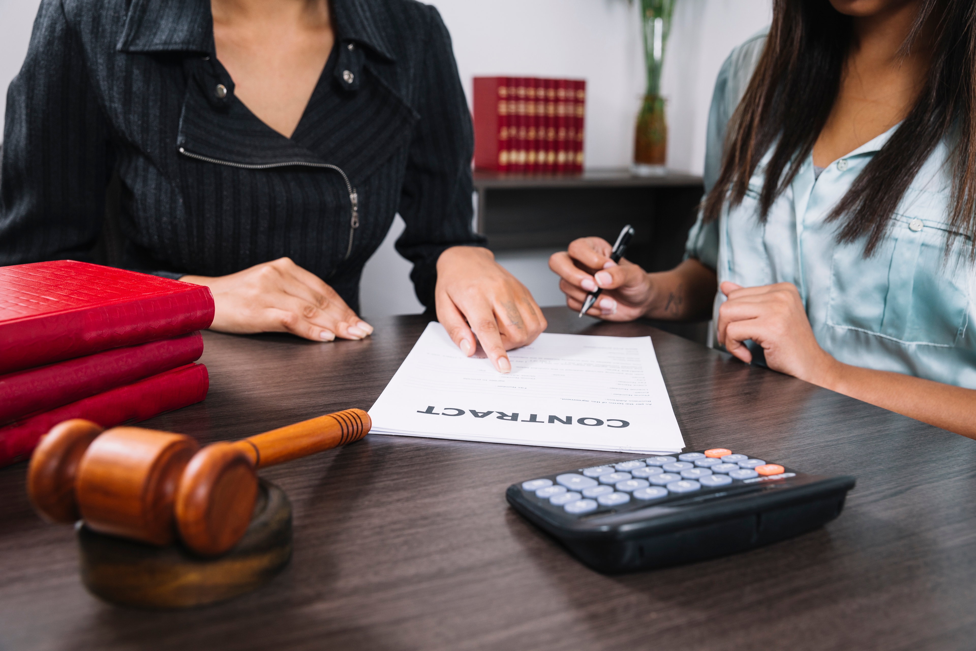 Black Woman Pointing Document Near Lady With Pen Table With Calculator Gavel